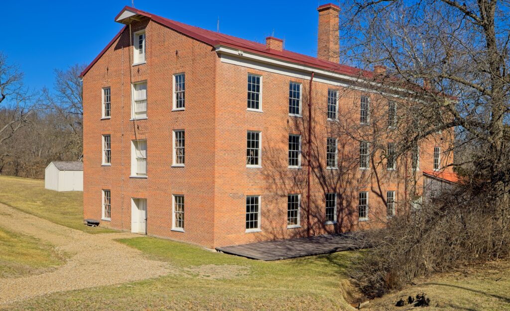 Image of a three-story brick building with several windows in a winter-season setting.