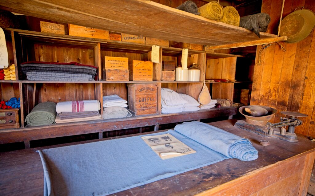 A general store display containing textiles, yarn, coffee, and flour.