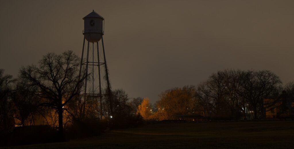A water tower silhouetted against a gray, cloudy sky.