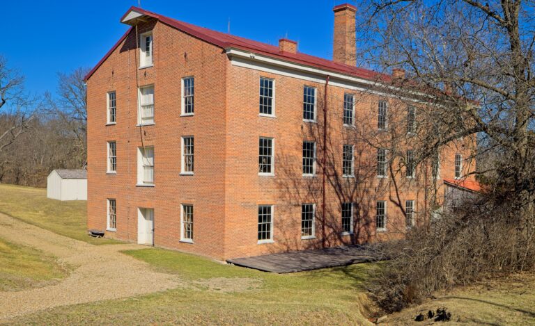 Image of a three-story brick building with several windows in a winter-season setting.