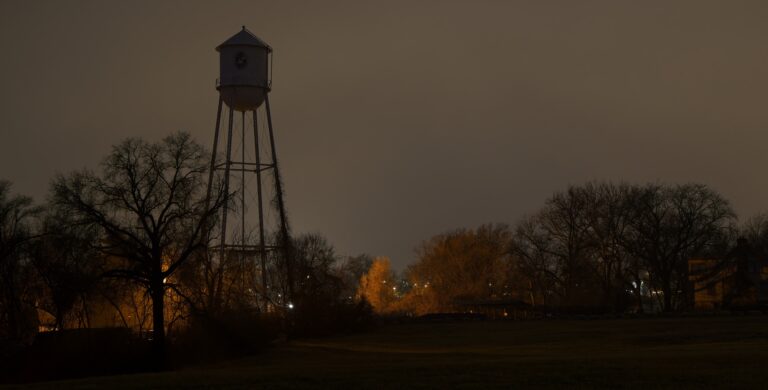 A water tower silhouetted against a gray, cloudy sky.
